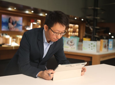 A man in a suit writing on a tablet.