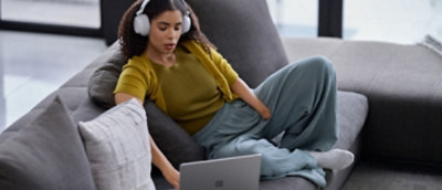 一位戴著耳機的女孩在使用膝上型電腦工作。