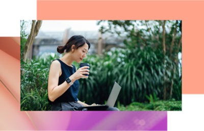 一位女士坐在長椅上，手裡拿著膝上型電腦和一杯咖啡。