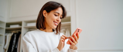 一名棕髮女性微笑並拿著手機。