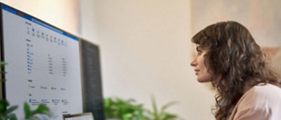 一位長捲髮的女士看著顯示文字 (는부 부터) 的電腦螢幕。