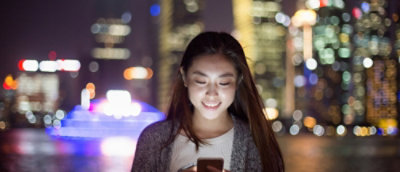 Een meisje dat naar de telefoon kijkt en lacht