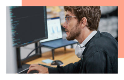 Een persoon die naar een monitor kijkt en op een toetsenbord typt