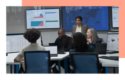 Een groep personen in een kantooromgeving met meerdere monitors en televisies aan de muur met gegevens in grafieken