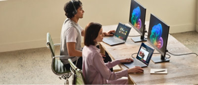 A woman works at a desk with multiple computer monitors displaying code and data.