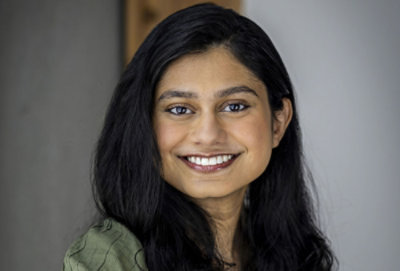 Smiling woman with long dark hair, wearing a green top.