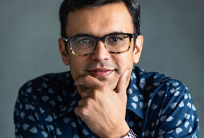 Close-up portrait of a person wearing glasses with hand on chin in a thoughtful pose