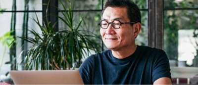 A man in glasses looking at a laptop.