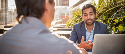 A man in a suit is talking to a man in a gray shirt.