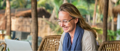 Улыбающаяся женщина в очках сидит в кресле.