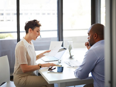 A man and woman sitting at a table with papers.