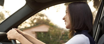 Eine Frau mit dunklen Haaren, die ein Auto fährt, Nahaufnahme ihrer Hände am Lenkrad.