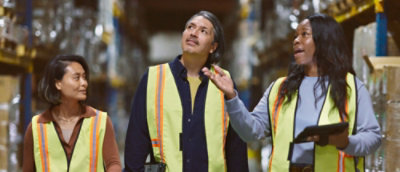 Ein Mann und eine Frau in gelben Mützen, die ein Tablet halten.