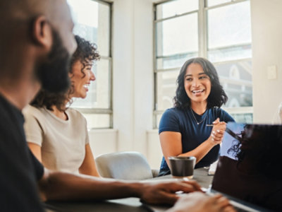 Personen, die an Schreibtischen mit mehreren Computern in einem Büroumfeld arbeiten.