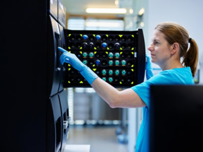Eine Frau mit blauen Handschuhen, die ein Gerät hält.