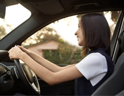 A woman in black and white shirt driving car