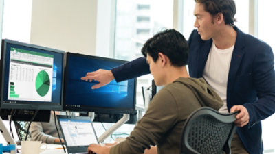 A man pointing at a computer screen displaying a pie chart.