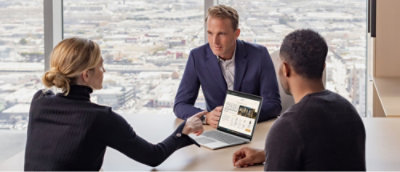 A group of people sitting at a table with a laptop in front of them.