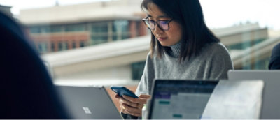 A woman wearing glasses and a turtleneck looking at a laptop.