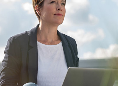Une femme est assise dehors avec un ordinateur portable 