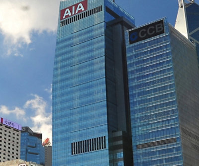 Un grand bâtiment en verre avec une enseigne rouge visible sur laquelle figure un texte.