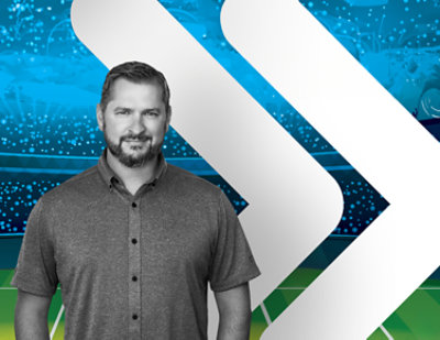  A man with a beard standing in front of a stadium.