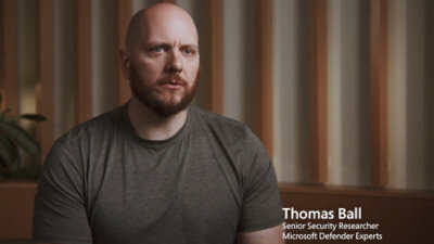 A man in a grey shirt is shown with a text overlay displaying Thomas Ball Senior Security Researcher Microsoft Defender Experts.