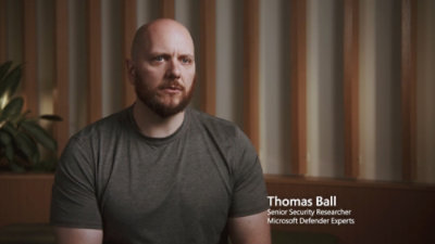 A man in a grey shirt is shown with a text overlay displaying Thomas Ball Senior Security Researcher Microsoft Defender Experts.