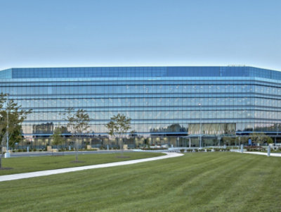 A large building with glass windows against a blue sky.