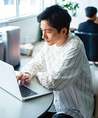  A person sitting at a table using a laptop.