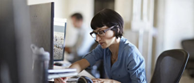 A women wearing glasses, working on a desktop.