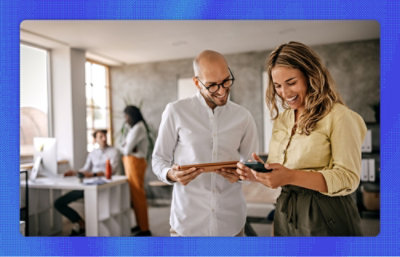 Two people looking at mobile phone and smiling.