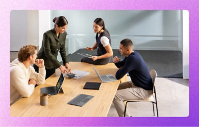 A group of people sitting around a table with laptops.