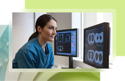 A woman in blue scrubs looking at computer screens.