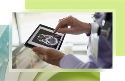 Person holding a tablet displaying a black and white brain scan image.