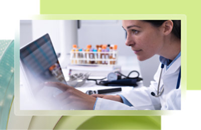 A woman in a white coat looking at a computer screen.