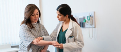 A woman checking the pulse of a patient in a hospital.