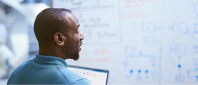 A man with short hair and a beard looking at a whiteboard.