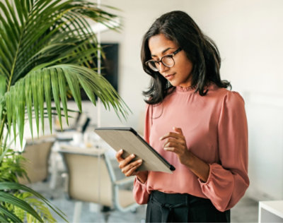 Femme portant des lunettes et tenant une tablette.
