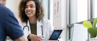 A woman in a white coat holding a tablet.