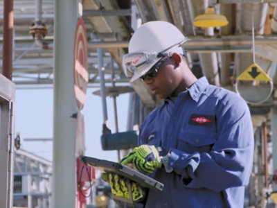An industrial worker, silhouetted and wearing helmets.