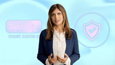 A person wearing a blue blazer and white shirt standing in front of a screen with the text Security.