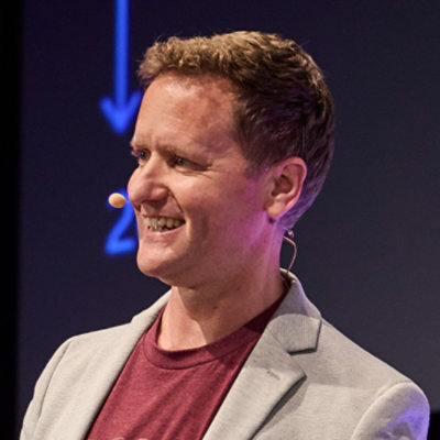 Close-up of a person wearing a headset microphone, speaking on stage.