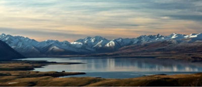 A lake with mountains in the background and a blue sky with clouds.