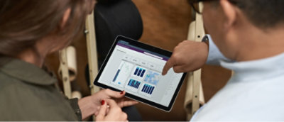Two people collaborating, reviewing data visualizations and charts displayed on a tablet.