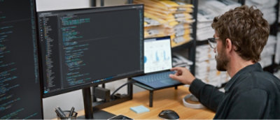 A man in a black shirt using a laptop at a desk.