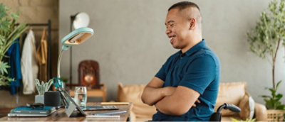 A man in a blue shirt sitting at a table with his arms crossed.