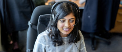 A women sitting at desk and wearing a headset
