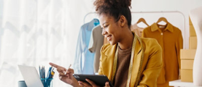 A lady holding digital pen and looking at a laptop.