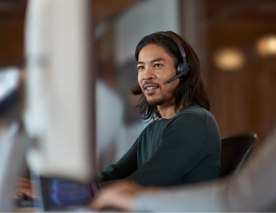 A man wearing a headset looking at a computer screen.